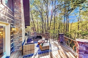 Eine Holzterrasse mit Steinmauern, Sitzgelegenheiten im Freien und Blick auf Bäume.