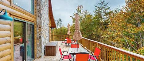 A wooden deck with outdoor seating, stone walls, and a view of autumn foliage.