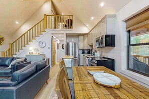 Eine moderne Küche mit Essbereich, einer Treppe und einem Wohnzimmer mit Sofa.