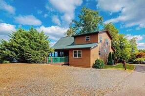 A two-story wooden house with a green roof, a porch, and a gravel driveway. - Amazing  Pet Friendly chalet w/ mountain views, wraparound porch, & hot tub (Murphy)