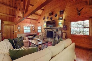 Ein Blockhaus-Interieur mit Kamin aus Stein, Holzwänden und einer gemütlichen Sitzecke.