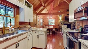 A wooden interior with a kitchen, dining area, and a fireplace. - Dog-Friendly with Hot Tub & Fire Pit Overlooking Golf Course at Lake Toxaway (Lake Toxaway)