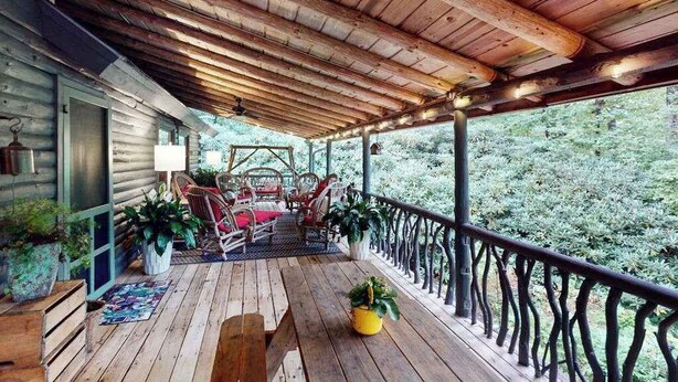 A wooden deck with chairs and potted plants, overlooking a forested area. - Dog-Friendly with Hot Tub & Fire Pit Overlooking Golf Course at Lake Toxaway (Lake Toxaway)