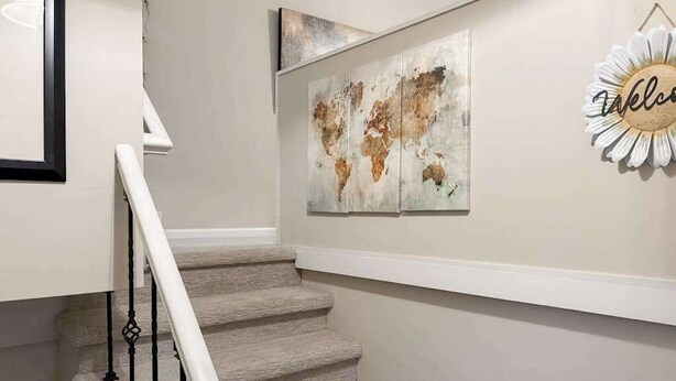 Een trap met een witte leuning, een wereldkaart op de muur en een 'Welcome' bord.