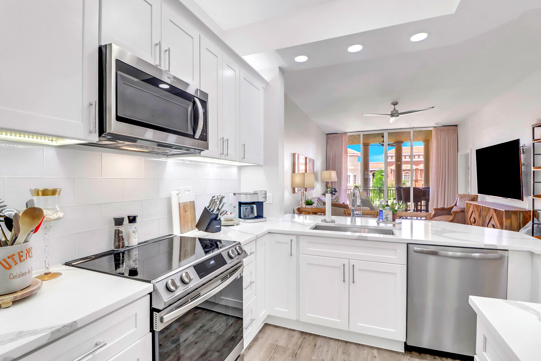 A modern kitchen with white cabinetry, a stainless steel range, and a dishwasher.