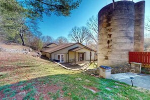 Ein Haus mit Veranda, einem großen zylindrischen Silo und einem eingezäunten Garten.