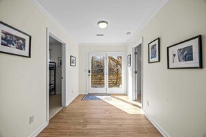Ein Flur mit Holzboden, weißen Wänden und gerahmten Bildern.