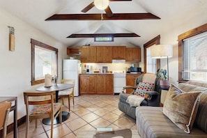 A compact kitchen with wooden cabinets, a dining table with chairs, and a sofa in a cozy living area. - Charming Brevard cottage perfect for a getaway with local shops & breweries! (Brevard)
