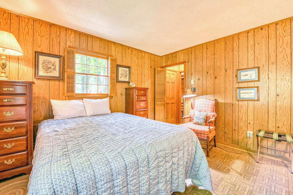 Un dormitorio con paneles de madera, una cama, un aparador y una silla.