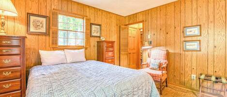 Un dormitorio con paneles de madera, una cama, un aparador y una silla.