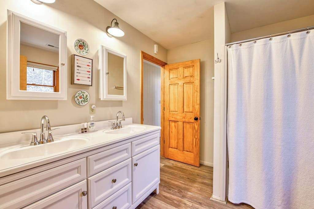 A bathroom with two sinks, a wooden door, and a shower curtain.