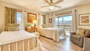 A bedroom with two beds, a ceiling fan, a sofa, and a view of the outdoors. - Balsam View (Waynesville)