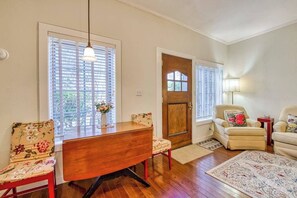 A dining area with a wooden table, chairs, and a window with blinds. - English Roses (Lake Junaluska)