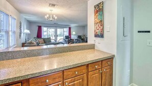 A kitchen with granite countertops, wooden cabinets, a chandelier, and a dining area with a sofa and chairs. - Beehive Condo (Lake Junaluska)