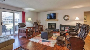 A living room with a fireplace, leather chairs, a sofa, and a television. - Beehive Condo (Lake Junaluska)