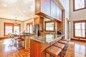 A spacious kitchen with wooden cabinets, a large island with bar stools, and a central island with a sink. - Lakeview retreat with Free Wifi, hot tub, fireplaces, patio, balcony, & grill (Mill Spring)