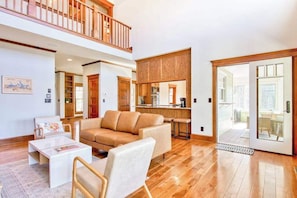 A spacious living area with a high ceiling, a wooden balcony, a kitchen, and a sliding glass door leading to an outdoor area. - Lakeview retreat with Free Wifi, hot tub, fireplaces, patio, balcony, & grill (Mill Spring)