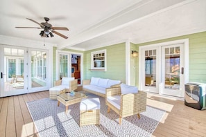 A spacious living area with a ceiling fan, wicker furniture, and a large window overlooking a deck. - Lakeview retreat with Free Wifi, hot tub, fireplaces, patio, balcony, & grill (Mill Spring)