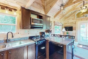 A wooden cabin interior with a kitchen featuring a stove, microwave, and sink. - Scenic Cabin w/ Private Hot Tub, Amazing Views, & Covered Porch. Nearby Skiing (Mars Hill)