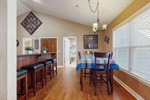 A dining area with a wooden table, chairs, and a bar with stools. - Mountain Ranch Home w/ Pool Table, Fire Pit & Porch Rockers (Hendersonville)