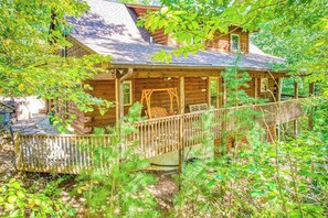 Eine Holzhütte mit Veranda, Schaukel und überdachter Brücke.