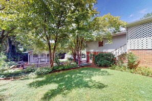 A residential property with a well-maintained lawn, a wooden deck, and a brick wall. - Vintage charmer in Lake Junaluska with mountain views, pool & sunroom (Lake Junaluska)