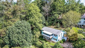 Ein zweistöckiges Haus, umgeben von dichtem Wald.