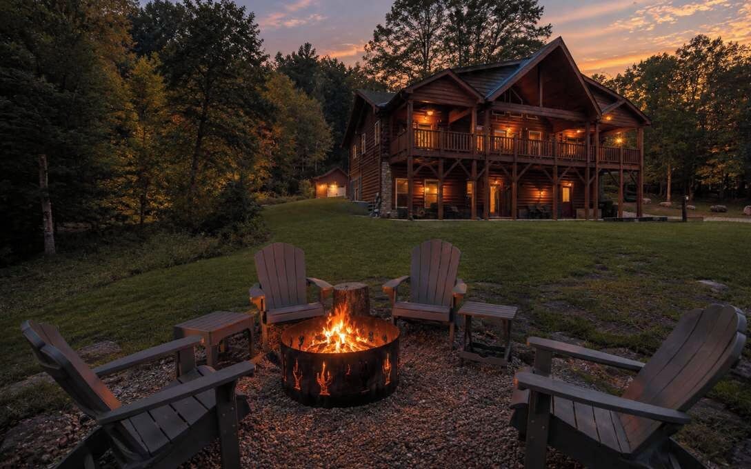 Eine Lodge mit Feuerstelle und Adirondack-Stühlen davor.