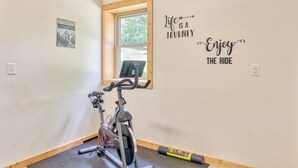Une pièce équipée d’un vélo d’appartement, d’une fenêtre et d’œuvres d’art motivantes accrochées au mur.
