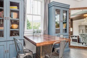 Ein Essbereich mit einem Holztisch, Metallstühlen und einem blauen Schrank mit Glastüren.