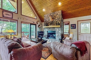 A cozy living room with leather sofas, a stone fireplace, and large windows. - Wildcat Retreat (Murphy)