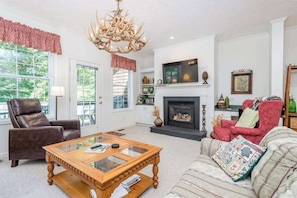 A living room with a fireplace, a television, and a chandelier. - Two-part villa near the slopes with hot tub, pools, golf on-site, & fast WiFi (Sapphire)