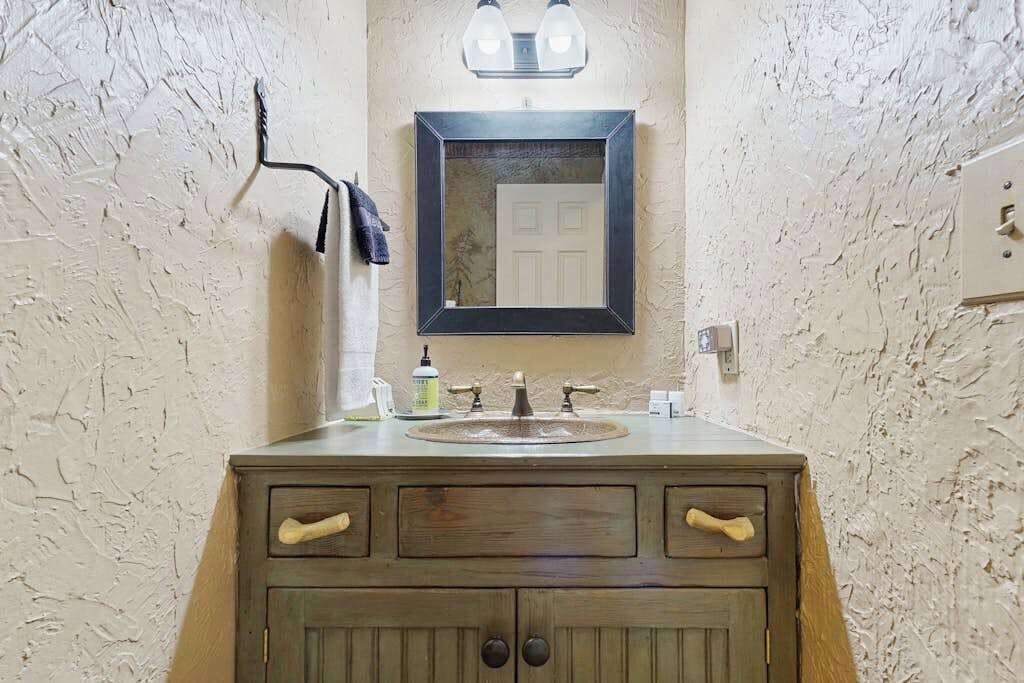 A bathroom with a wooden vanity, a mirror, a sink with a faucet, and a towel hanging on a rack.