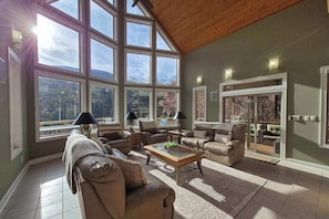 A spacious living room with large windows, a high ceiling, and a cozy seating area. - Mountain-View Escape on Rumbling Bald’s 14th & 15th Holes (Lake Lure)