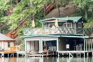 A houseboat with a balcony, a deck, and a small outdoor seating area.