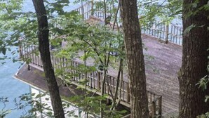 Une terrasse en bois, dotée de rampes de protection, qui offre une vue sur une étendue d’eau.