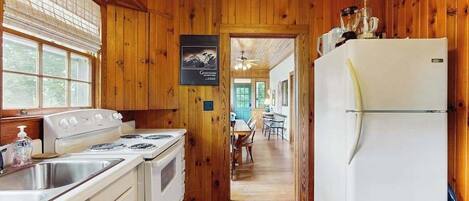 A wooden-paneled kitchen with a stove, sink, and refrigerator.