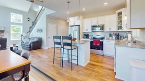 A modern kitchen with white cabinets, a central island, and a staircase leading to another level. - Secluded Mill Spring Retreat: Stunning Views, Luxury Amenities (Mill Spring)