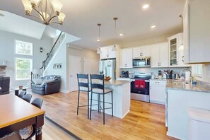A modern kitchen with white cabinets, a central island, and a staircase leading to another level. - Secluded Mill Spring Retreat: Stunning Views, Luxury Amenities (Mill Spring)