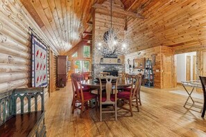Ein Blockhaus-Interieur mit Essbereich, Kamin und Holzwänden.