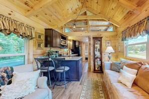 Ein Holzblockhaus-Interieur mit Küche, Essbereich und Wohnzimmer.