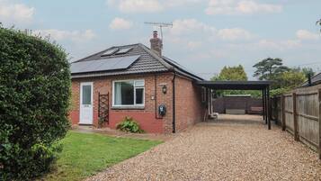 A house with a gravel driveway, a covered carport, and a brick chimney.