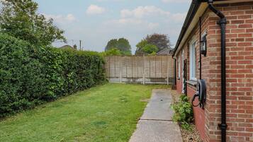 A brick house with a garden, a concrete pathway, and a wooden fence.