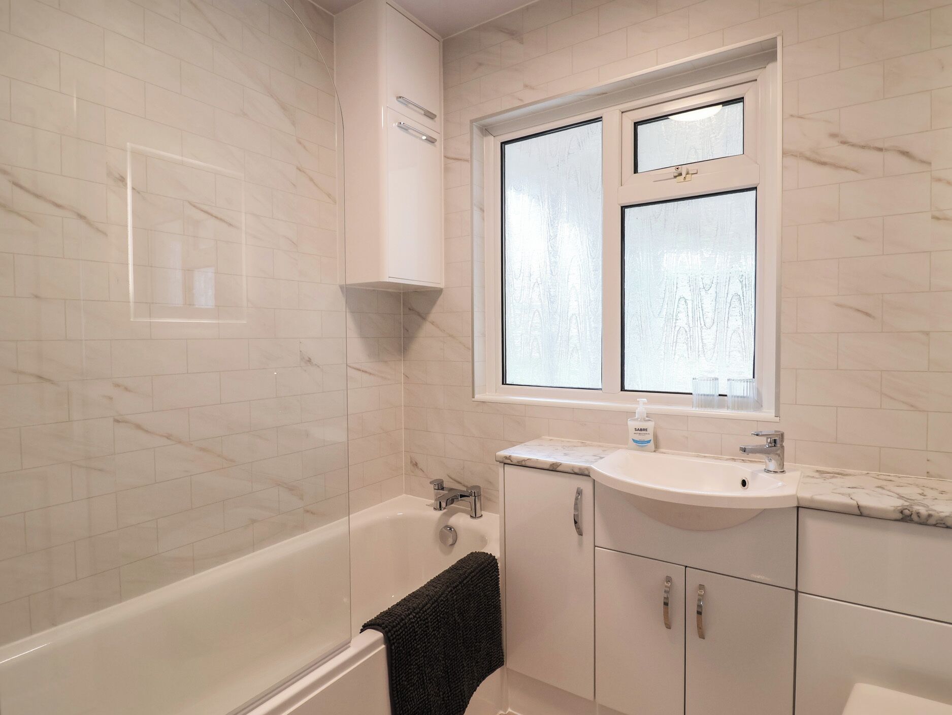 A bathroom with a bathtub, a sink, and a window.
