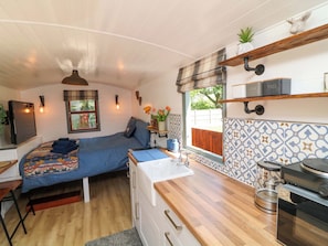 A compact bedroom with a bed, bedside table, and a window. - Lake View Shepherds Hut (Lincoln)