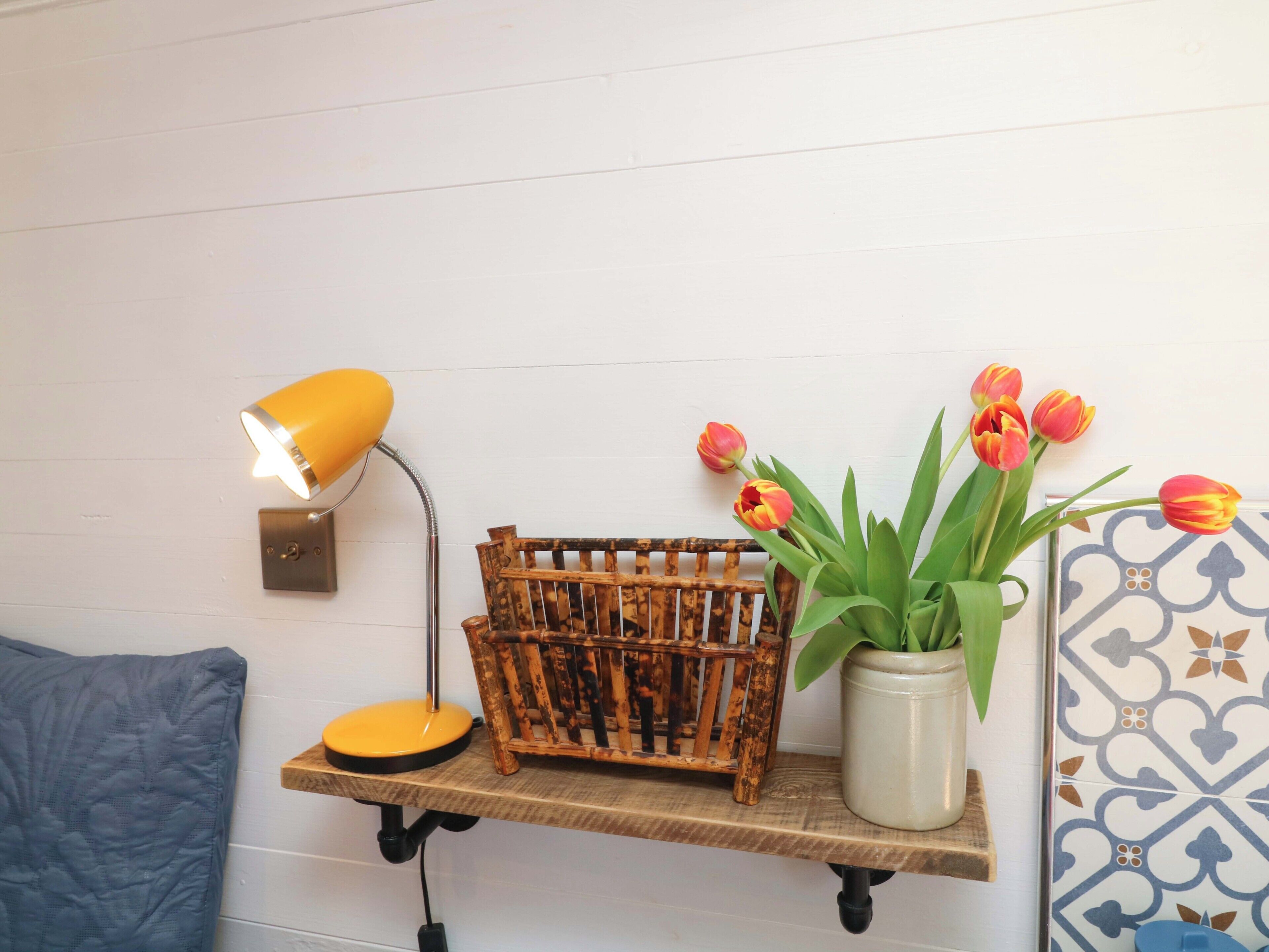 A shelf with a lamp, a basket, and a vase with flowers.
