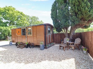 A wooden cabin with a porch, a dining table, and two chairs. - Lake View Shepherds Hut (Lincoln)