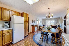 A kitchen with wooden cabinets, a white refrigerator, and a dining area with a round table and chairs.
