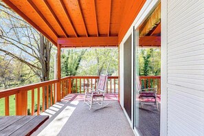 A covered outdoor area with a wooden deck, a rocking chair, and a bench.