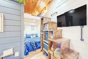 Ein Zimmer mit einem Bett, Holzregalen, einem Fernseher und einem Willkommensschild.